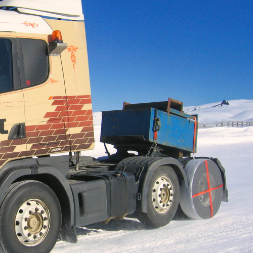Calcetín para neumáticos AutoSock montado en una rueda de camión, conduciendo sobre nieve en un paisaje invernal