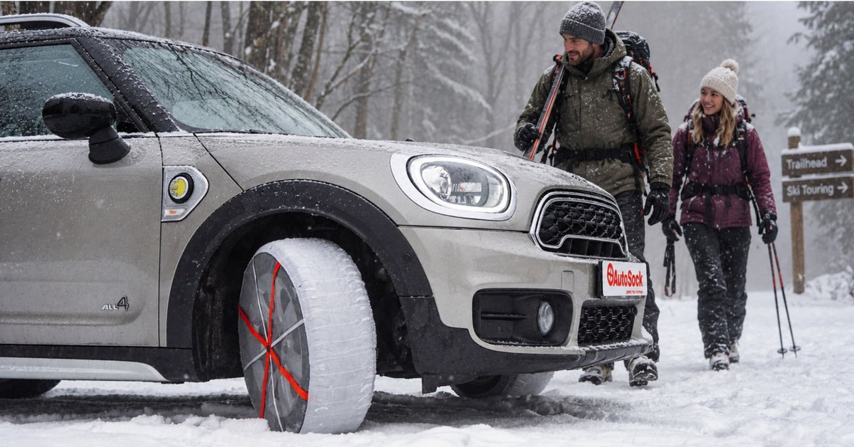 Cadenas de nieve textiles montadas en las ruedas delanteras de un Mini Cooper sobre la nieve con un fondo de niebla