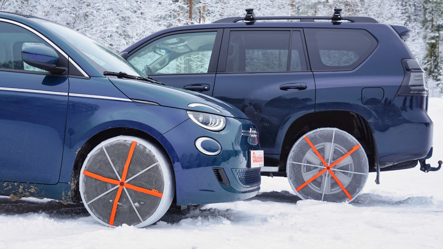 Vista frontal de cadenas de nieve textiles montadas en los neumáticos delanteros del Fiat 500 y en las ruedas traseras del vehículo todoterreno Toyota