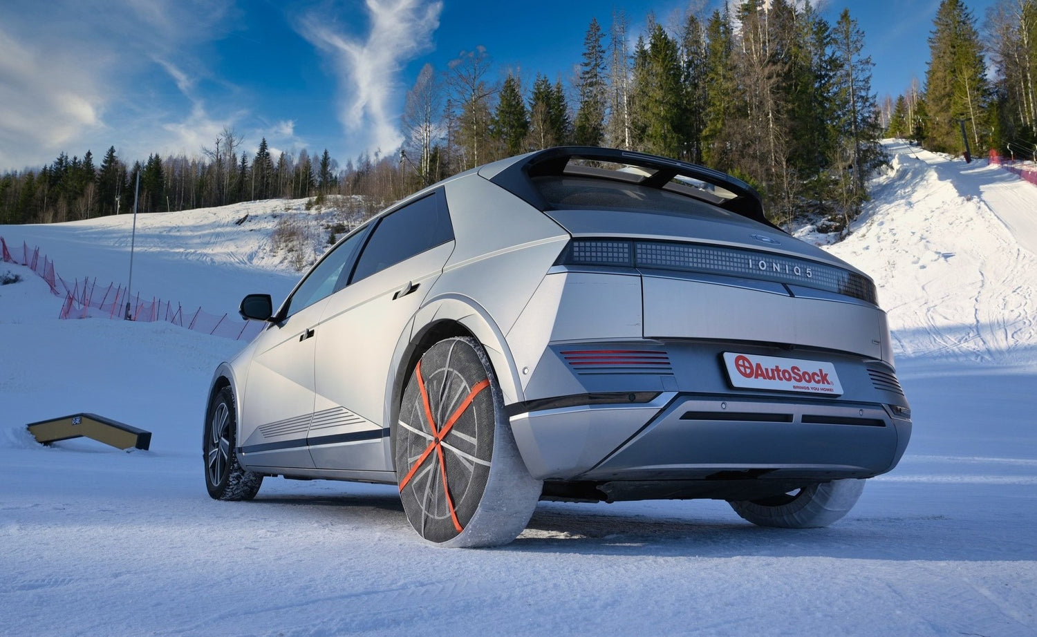 AutoSock montado en las ruedas traseras de un automóvil, de pie sobre la nieve en la naturaleza invernal